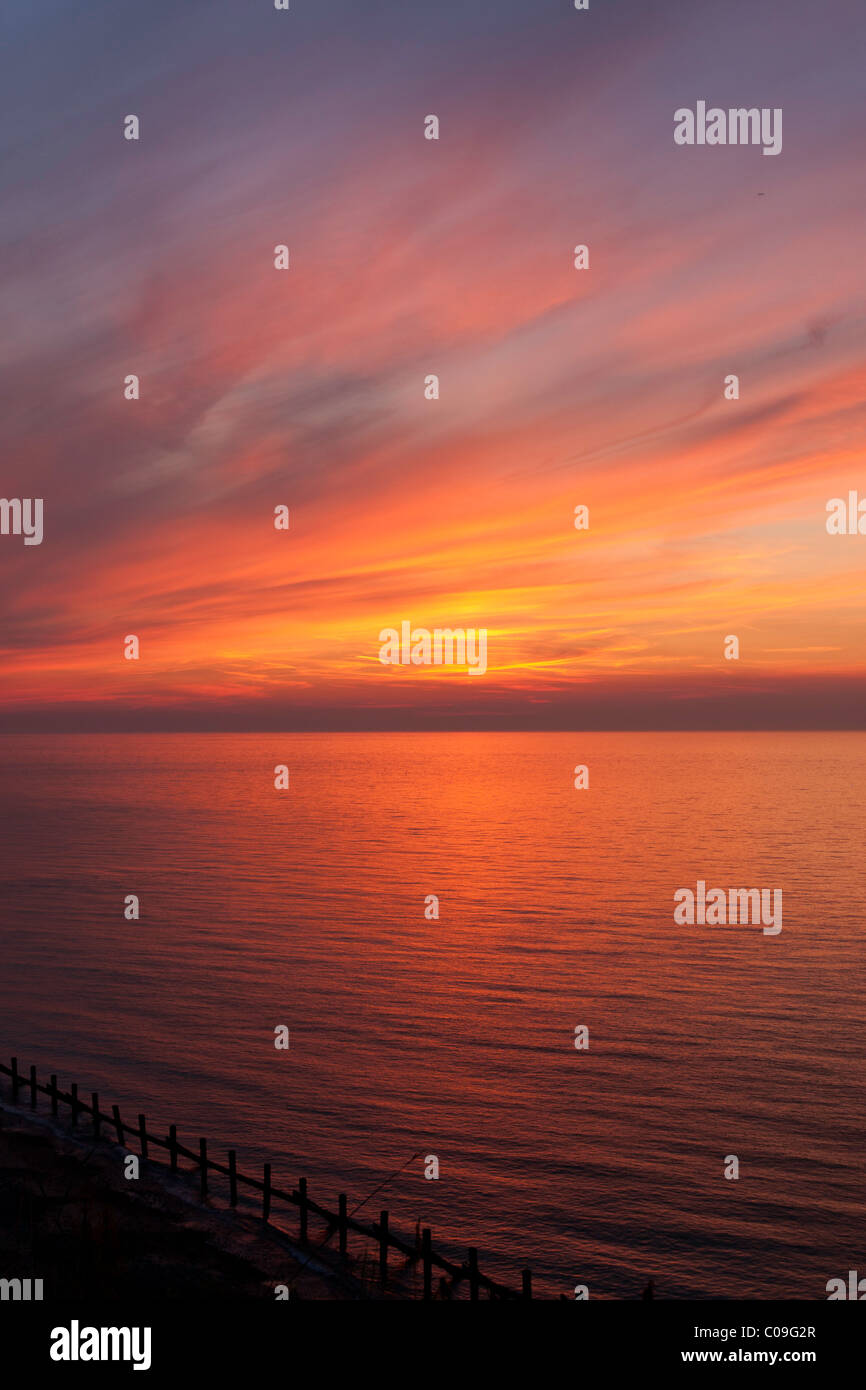 A beautiful sunset of orange, red and blue over the horizon of a calm sea. Stock Photo
