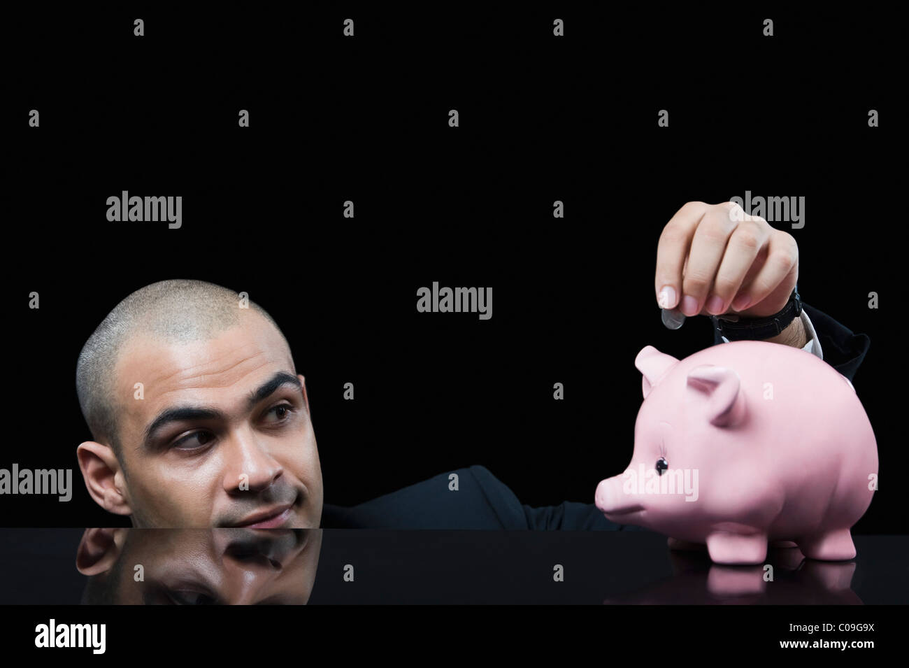 Businessman inserting a coin into a piggy bank Stock Photo - Alamy