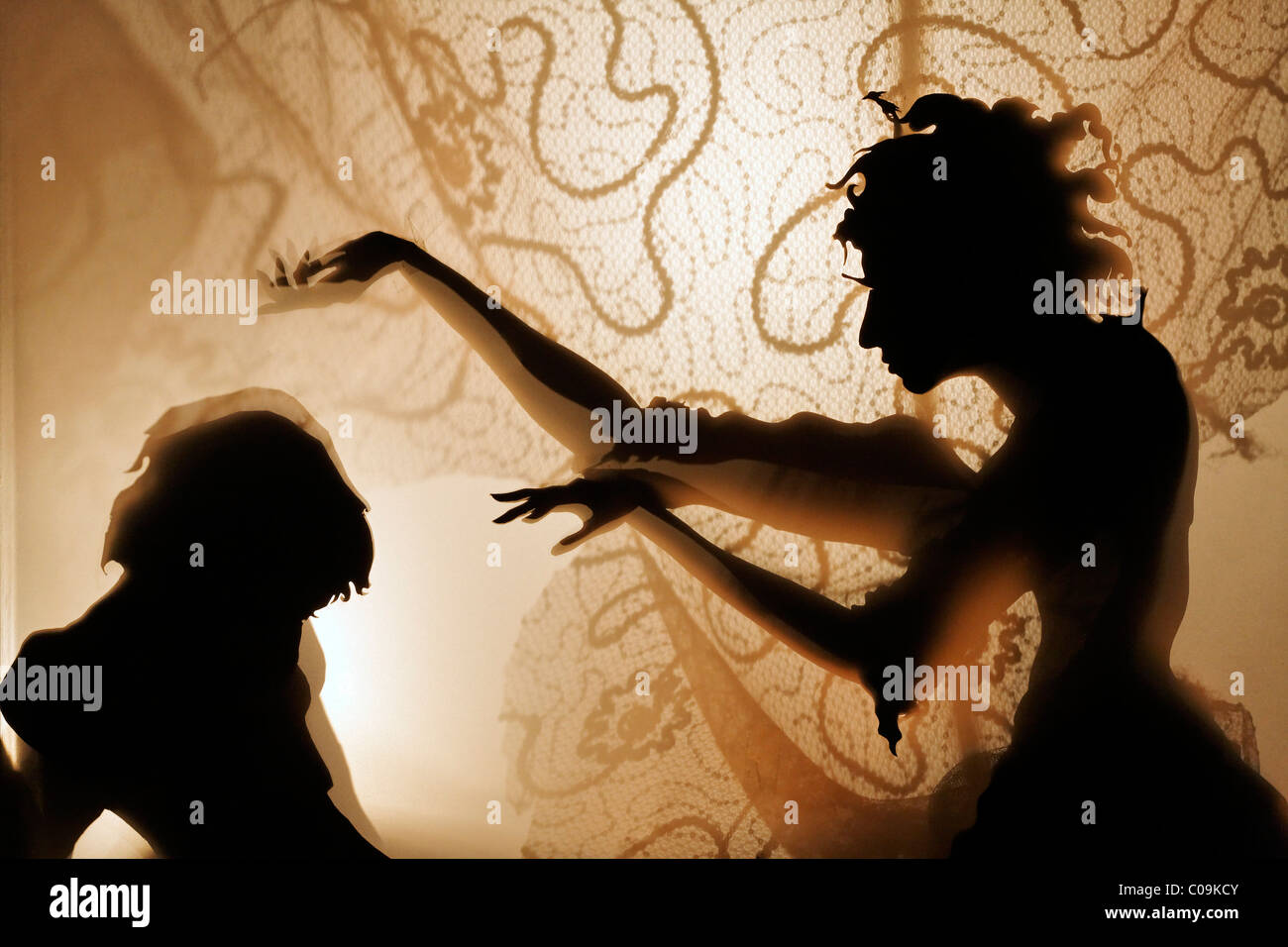 Woman bewitches a man, projection of silhouette figures on an illuminated curtain, shadow theater, tour Kunstakademie Art Stock Photo
