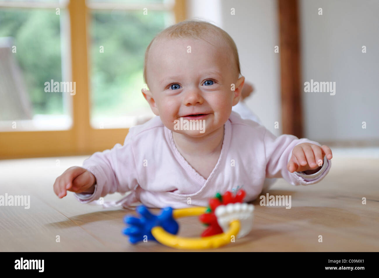 Small baby, 4 months, lying on her belly, with teether Stock Photo Alamy