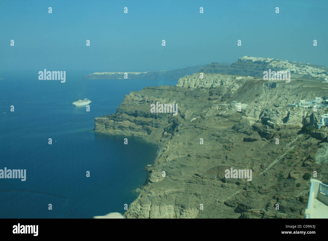 a super yacht dwarfed by the magnificence of the Santorini crater Stock Photo