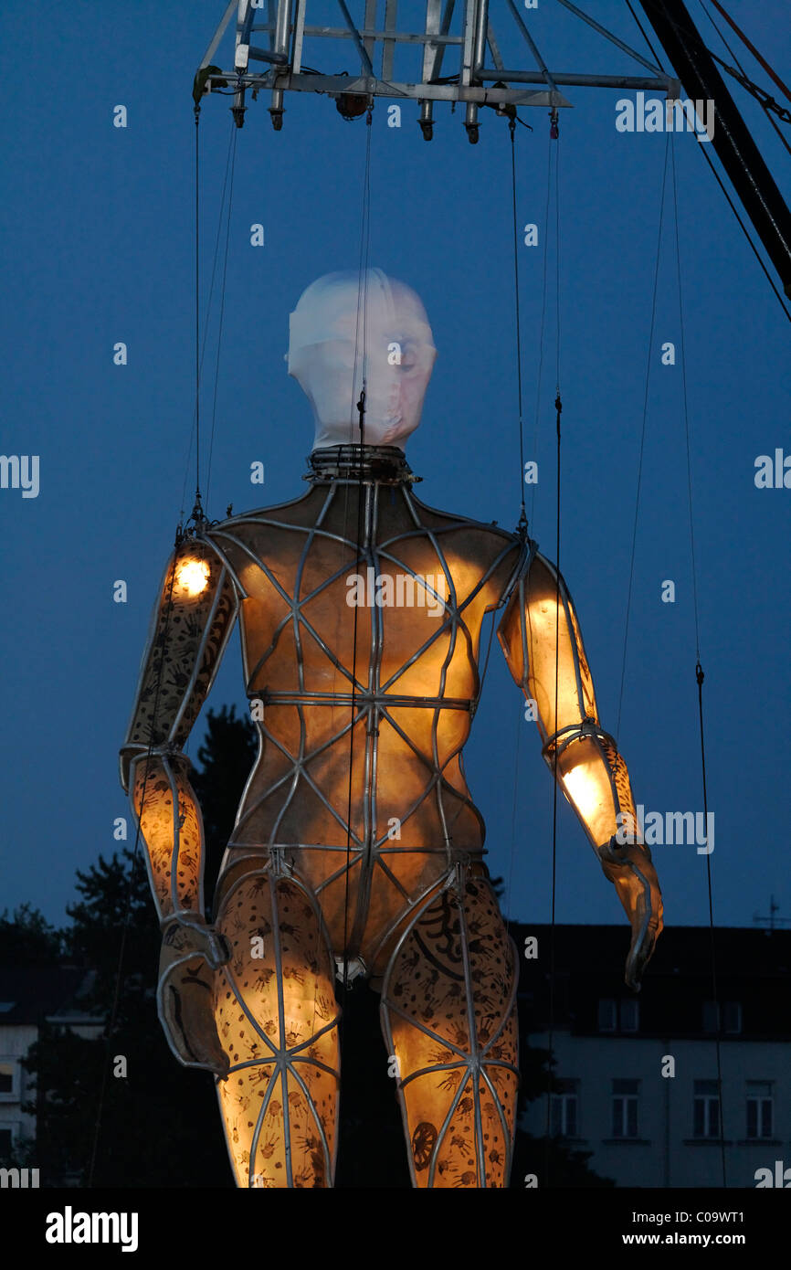 Illuminated giant figure hanging on ropes, Global Rheingold, open-air theater by La Fura dels Baus, Duisburg-Ruhrort Stock Photo