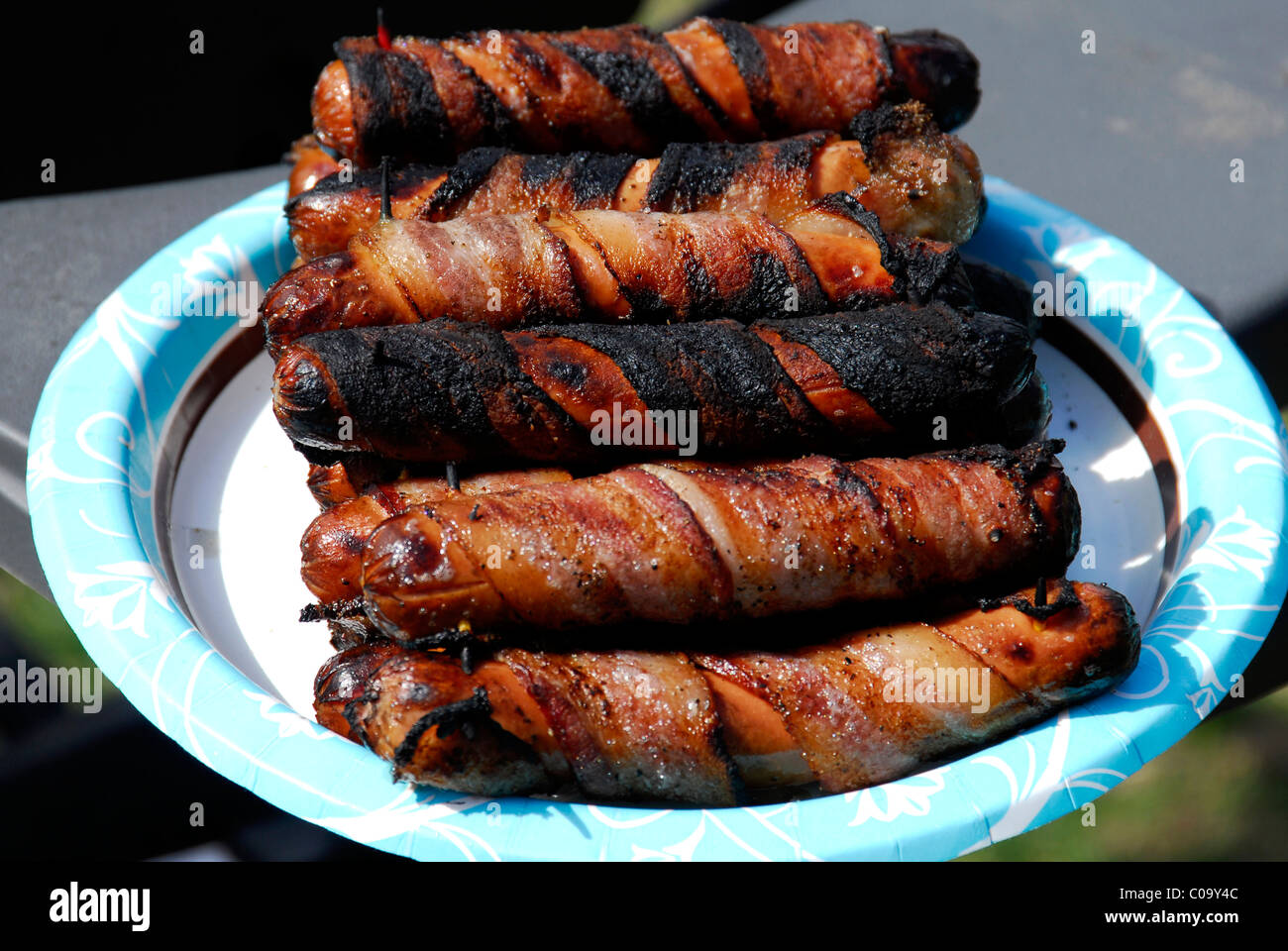 Bar-b-q Hot Dogs wrapped in bacon stacked on a paper plate Stock Photo