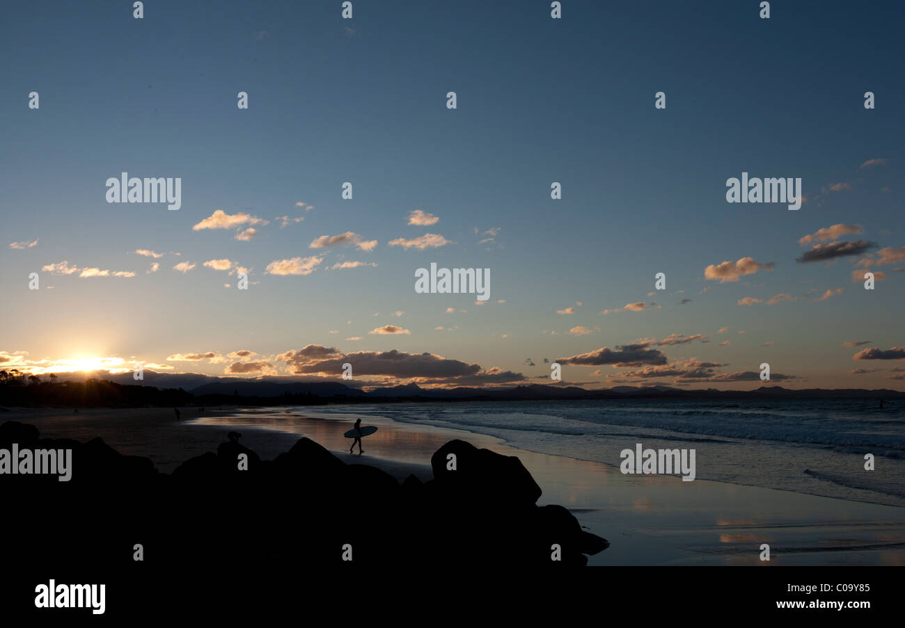 Single surfer enters water at dusk. Byron Bay, New South Wales, Australia Stock Photo