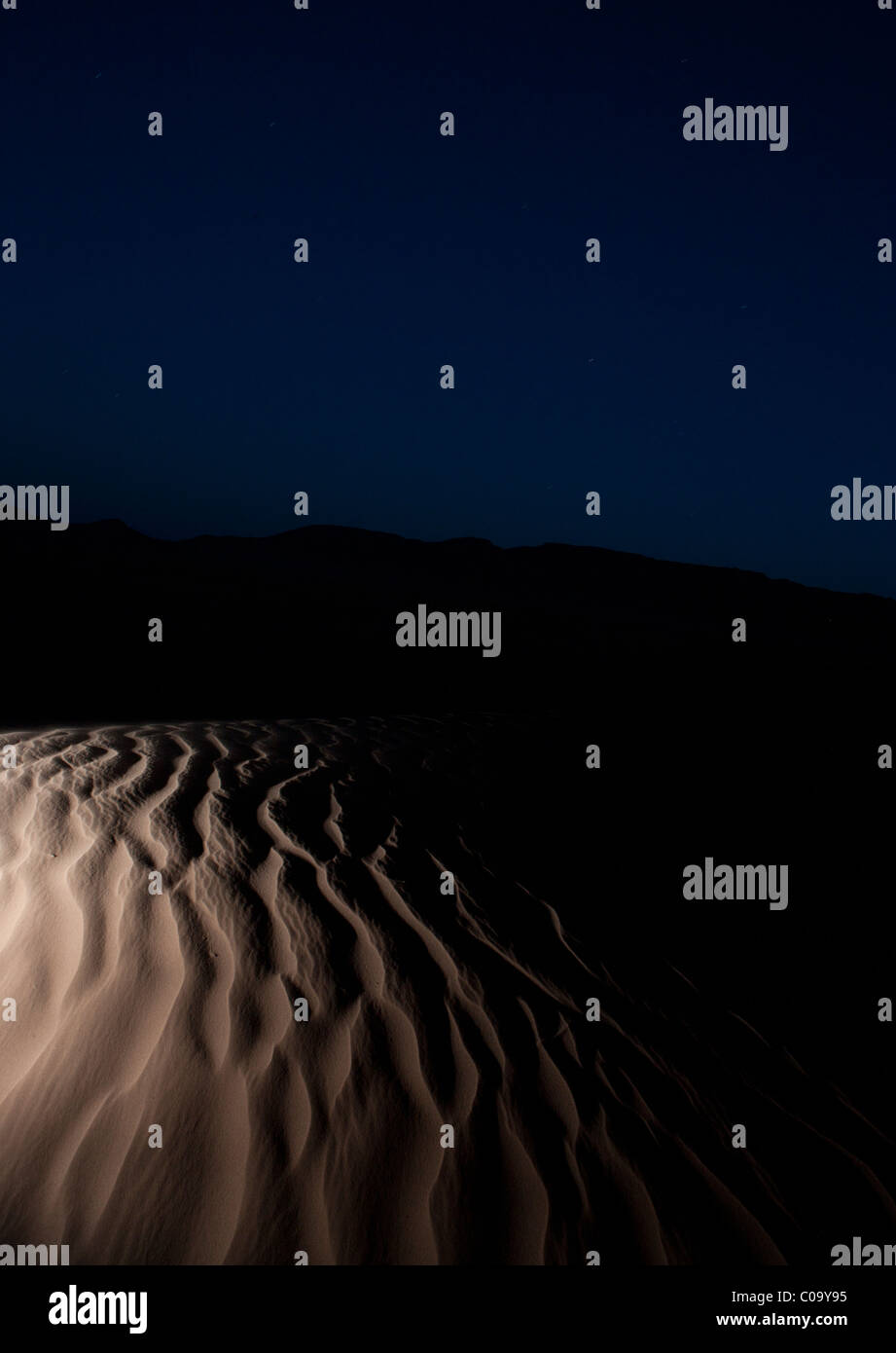 Sand dunes (Ergs) in Sahara desert caused by  aeolian processes at night showing texture left in sand by wind forces. Morocco. Stock Photo