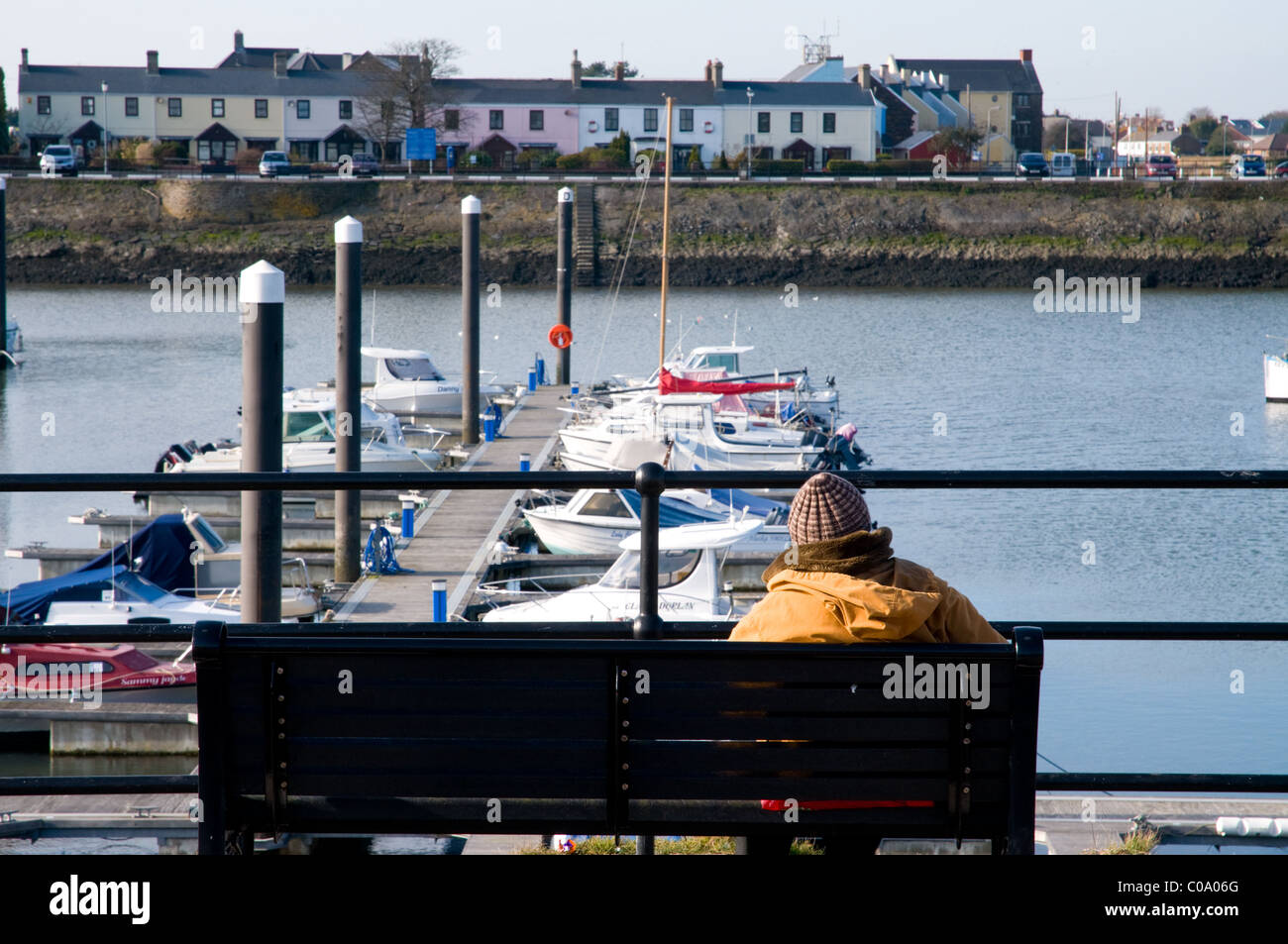 Old elderly lady sitting on bench overlooking Bury port harbour, Carmarthenshire, West Wales Stock Photo