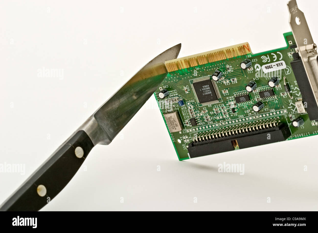 Sharp knife cutting into a circuit board Stock Photo