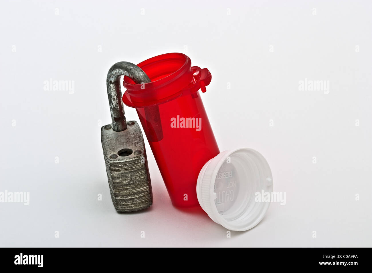 Empty prescription bottle with white plastic cover leaning on an open pad lock Stock Photo