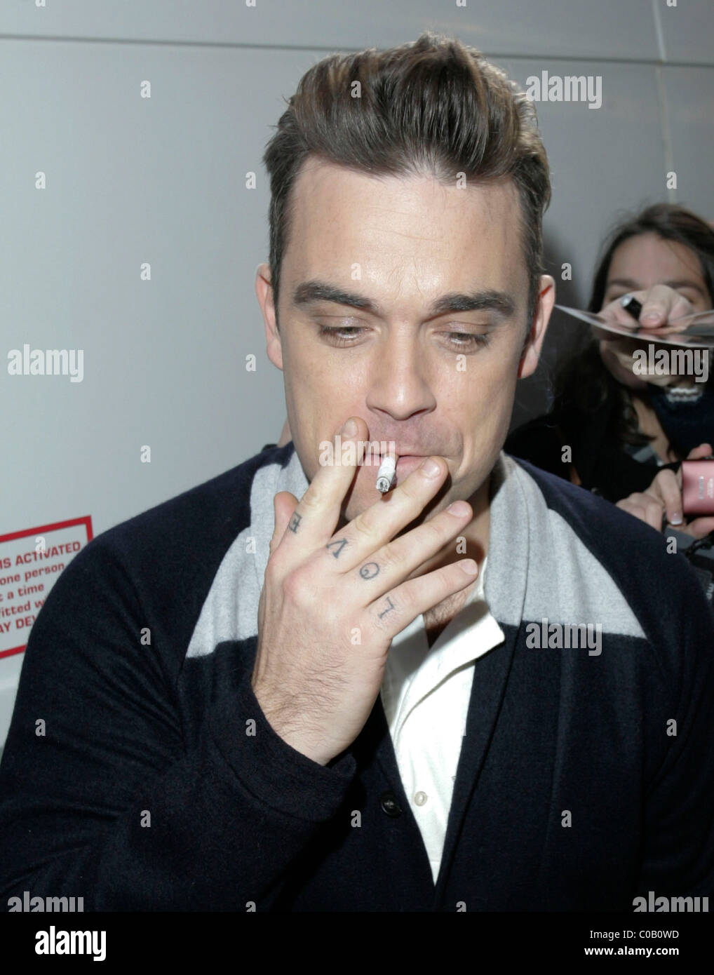 does robbie williams smoke cigarettes Robbie Williams smokes a cigarette outside The Royal Albert Hall. London,  England - 12.11.09 Stock Photo