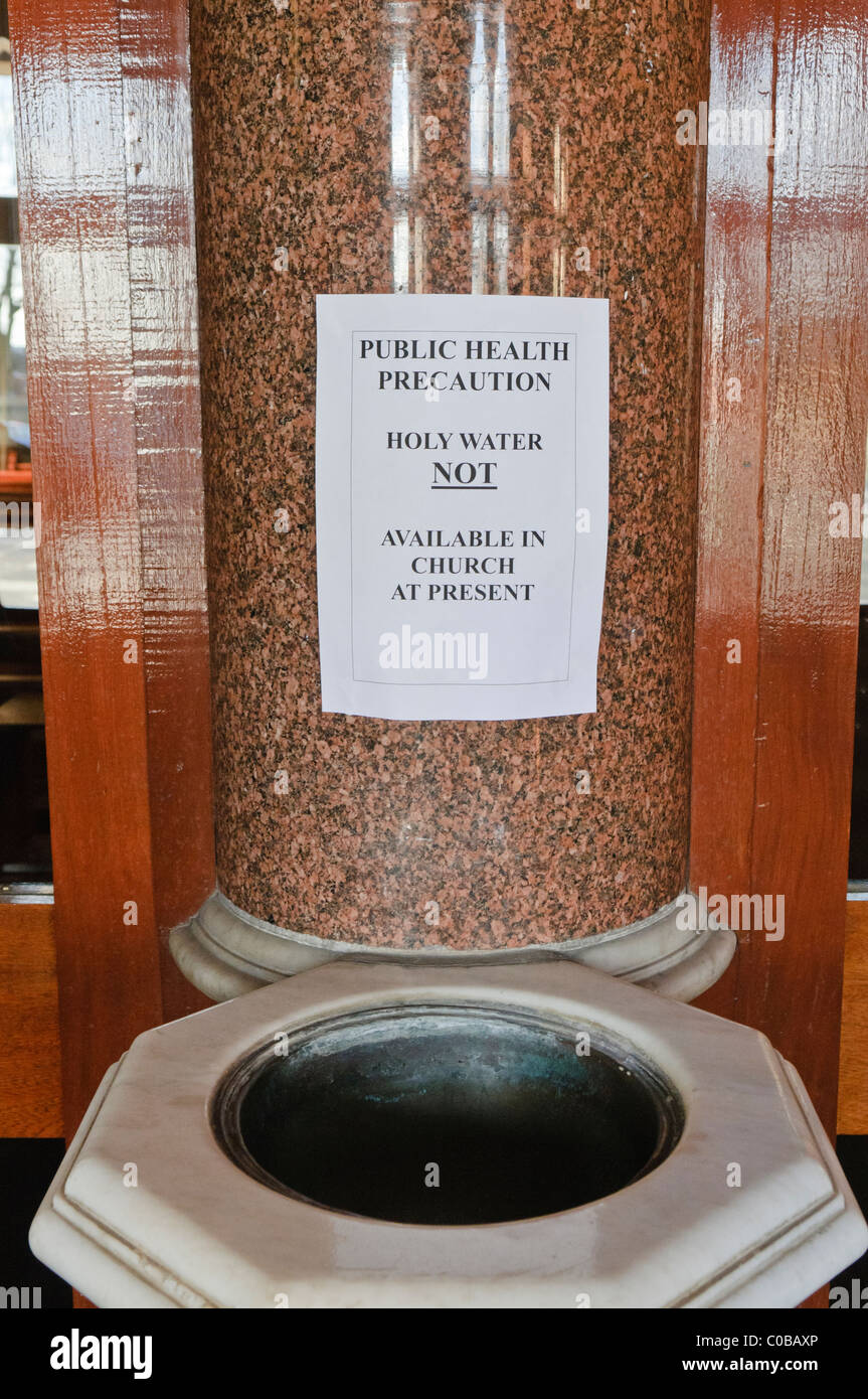 Sign at a holy water font in a Roman Catholic chapel 'Public health precaution.  Holy water not available in church at present' Stock Photo