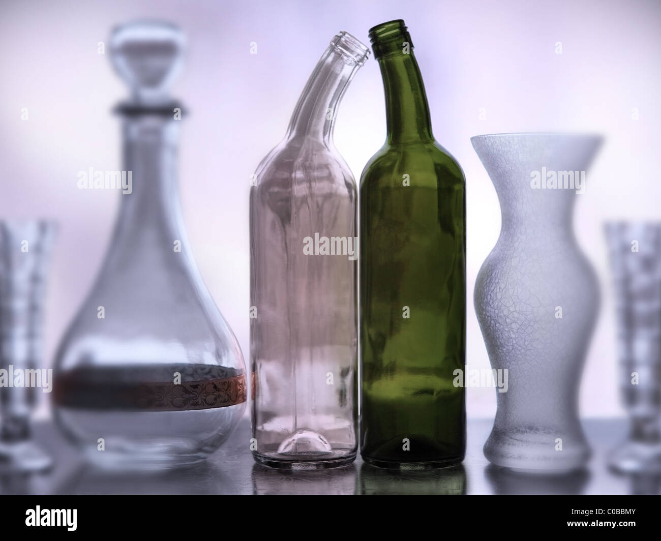 wine bottles straining their necks to touch each other among different glass containers. Stock Photo