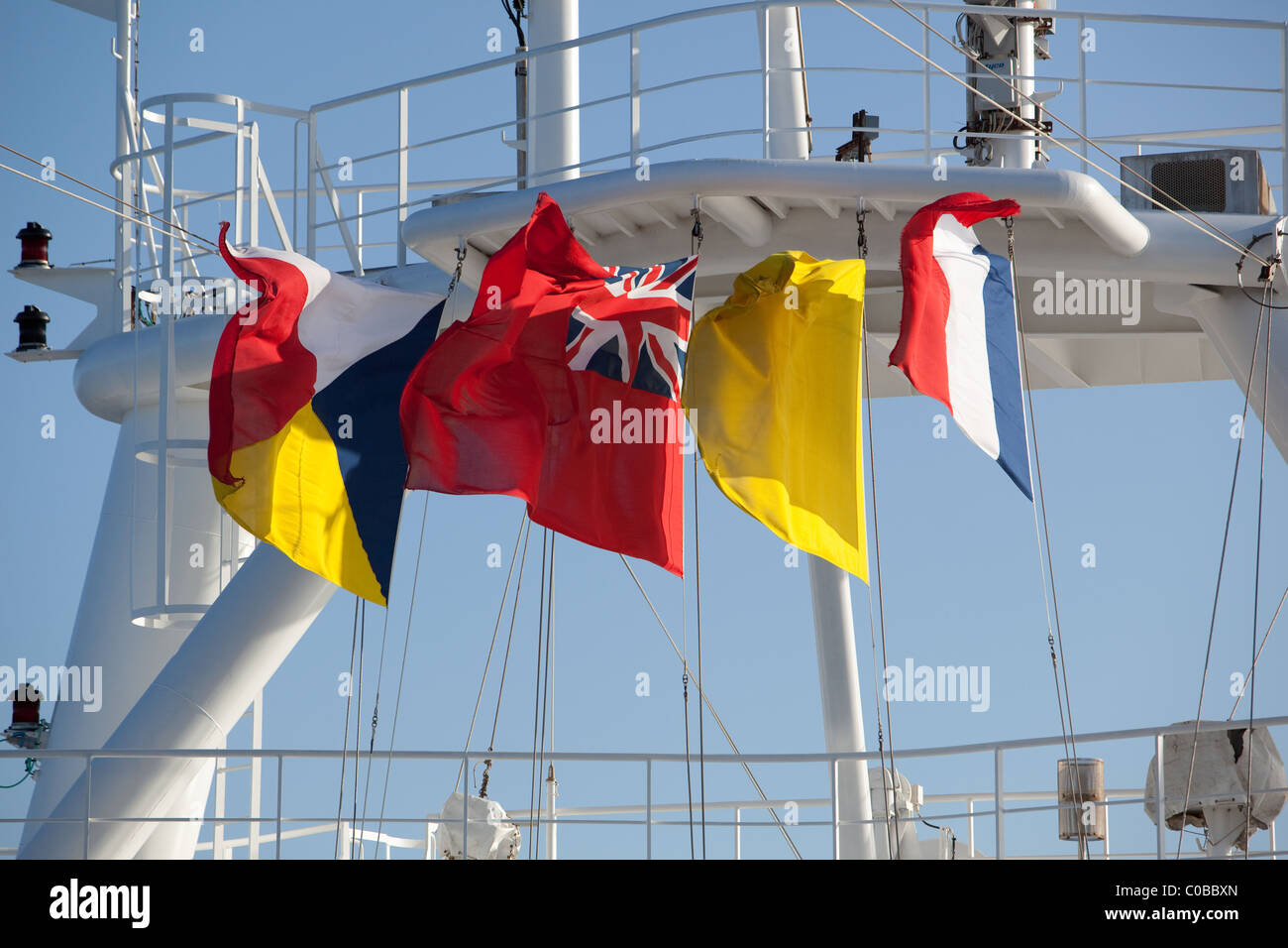 Ships flags flying in the wind including the red ensign while visiting French port.. Stock Photo