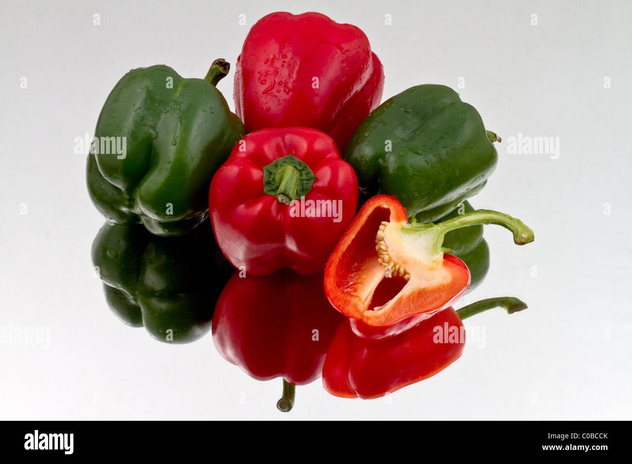 Red and green bell peppers and halved red bell pepper on reflective bacground Stock Photo