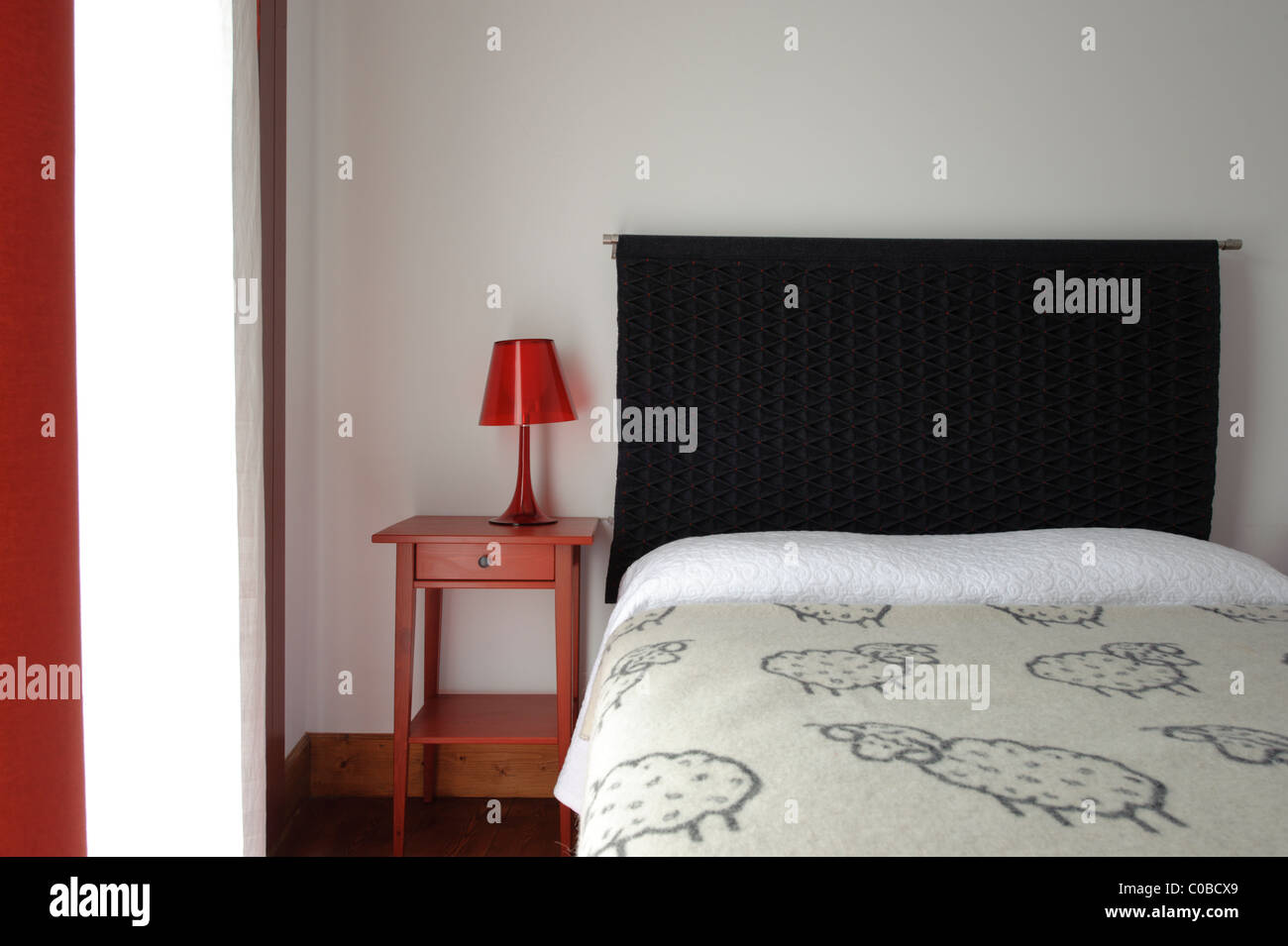 Bedroom bed with bedside table with red lamp Stock Photo