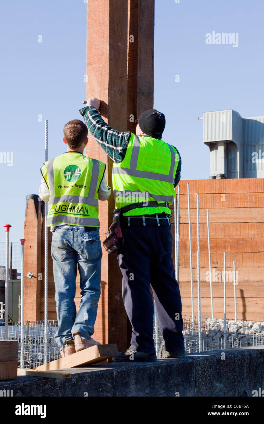 Construction of timber wall at Whitstable Harbour by workers not wearing hard hats on site Stock