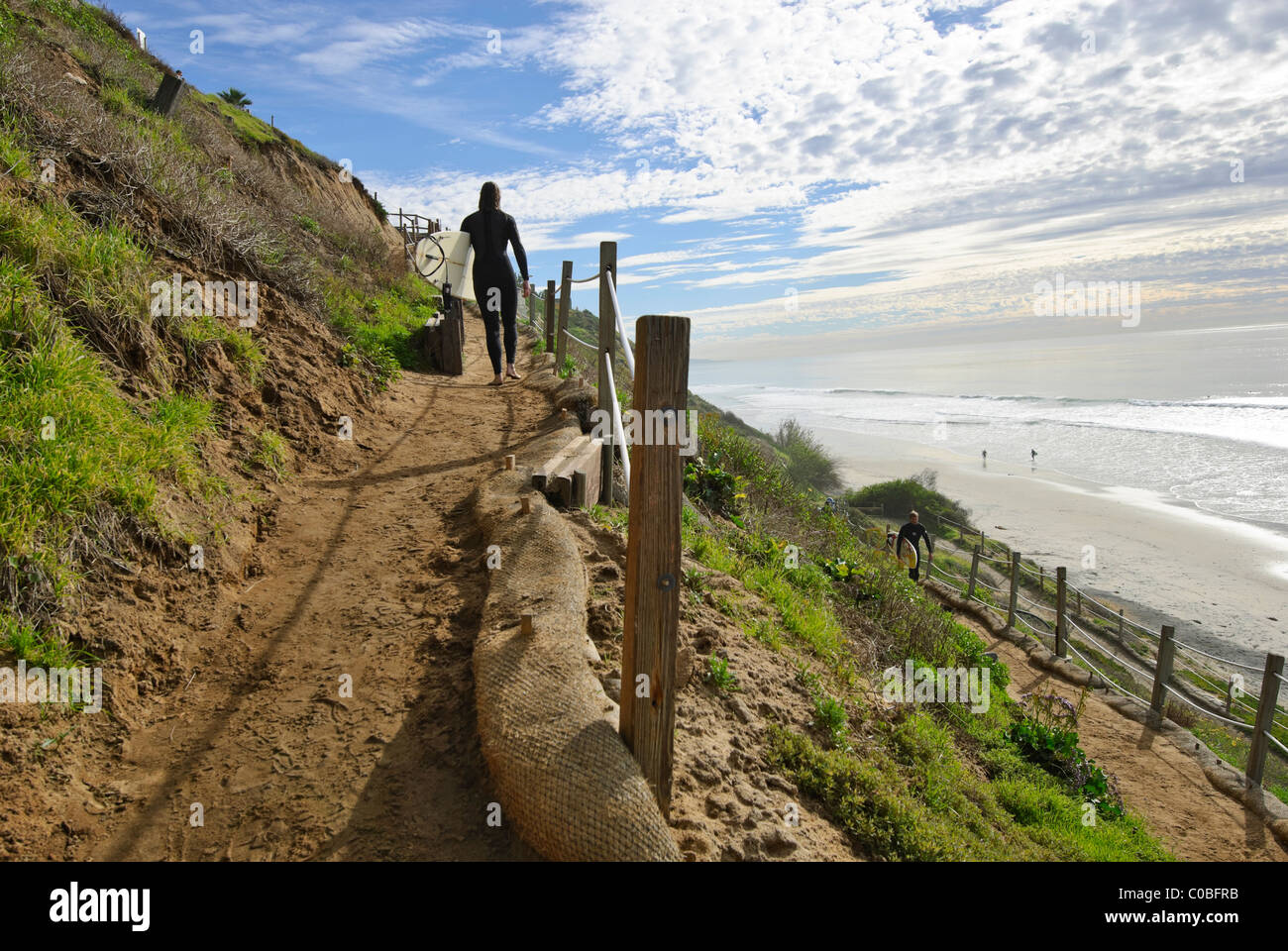 Surfers climbing a coastal bluff trail at Beacons Beach in Encinitas, California. Stock Photo