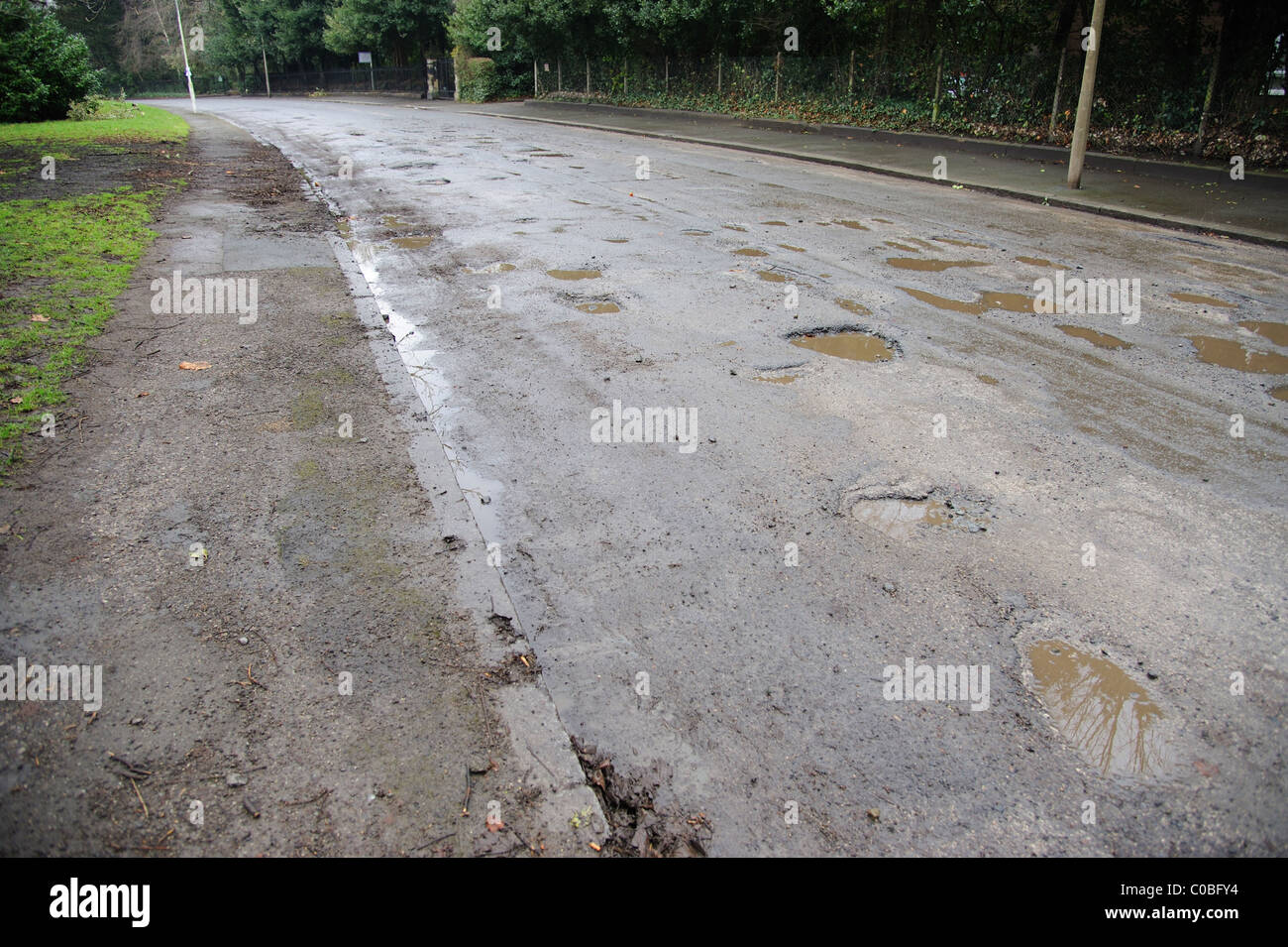 Road in need of repair. Numerous potholes caused by two severe winters. Stock Photo