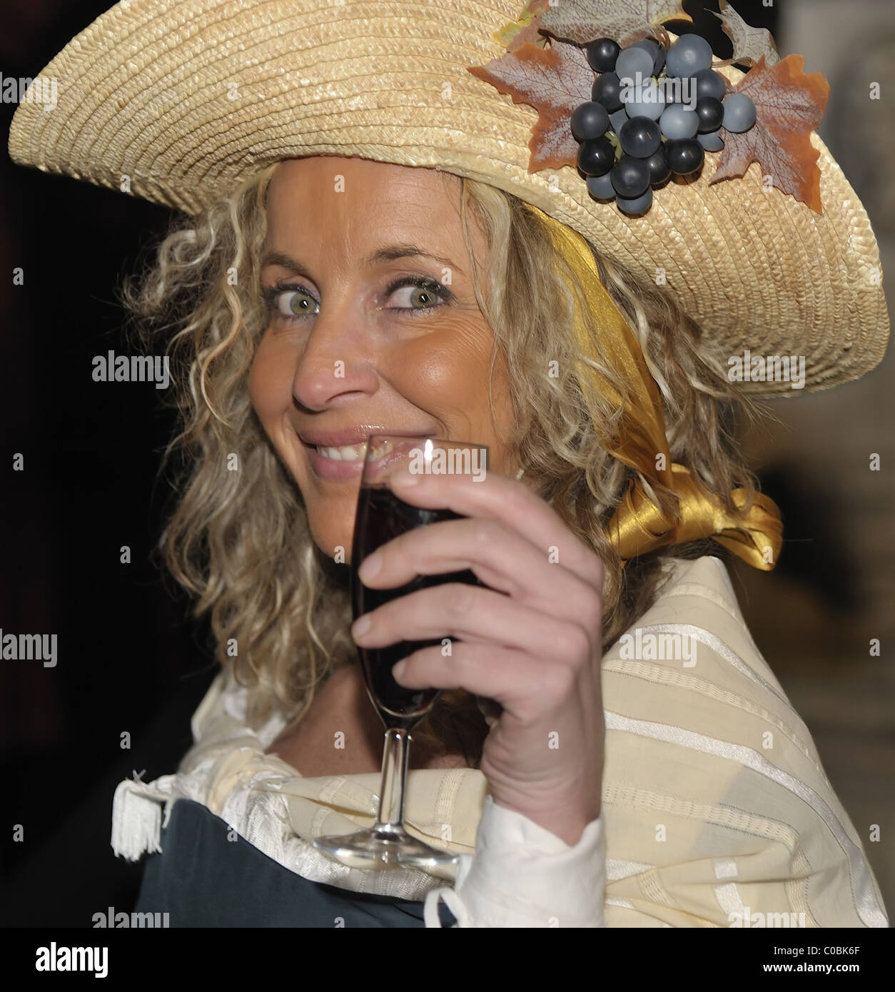 A young woman wearing a 19th Century waitress costume poses witha glass