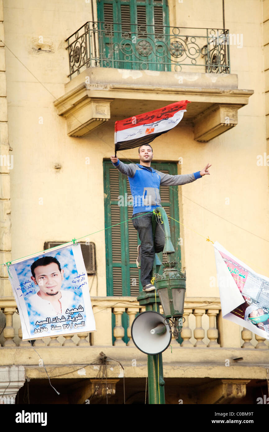 A man waves an Egyptian flag atop a lamp post in Tahrir Square hours before Hosni Mubarak steps down from office on Feb.11, 2011 Stock Photo
