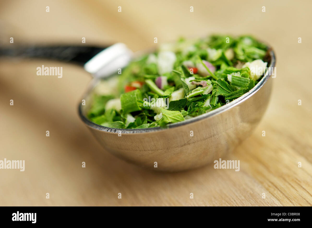 One tablespoon full of salad herbs in a measuring spoon. Stock Photo