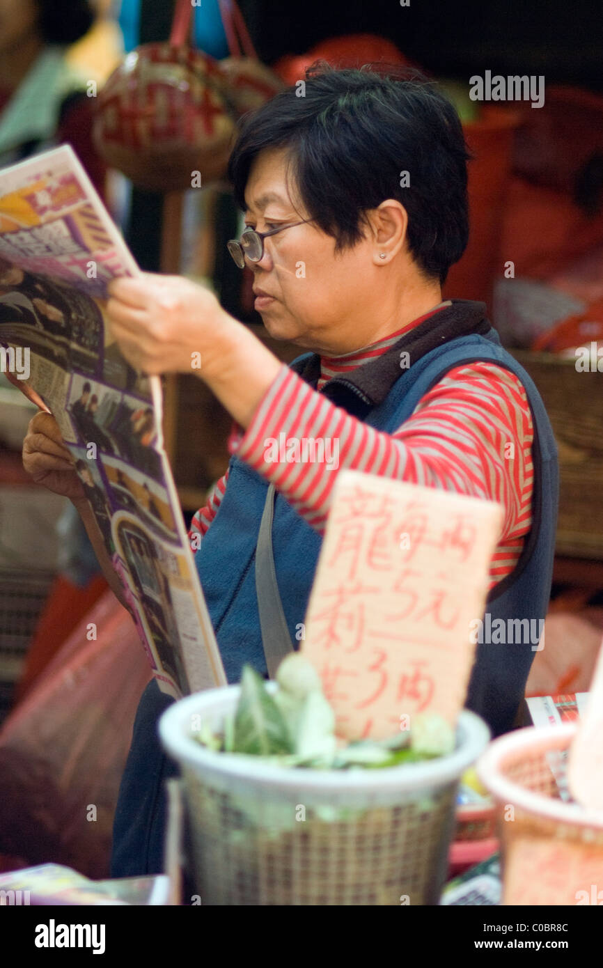 Chinese/Hong Kong woman reading a newspaper in a market Stock Photo - Alamy
