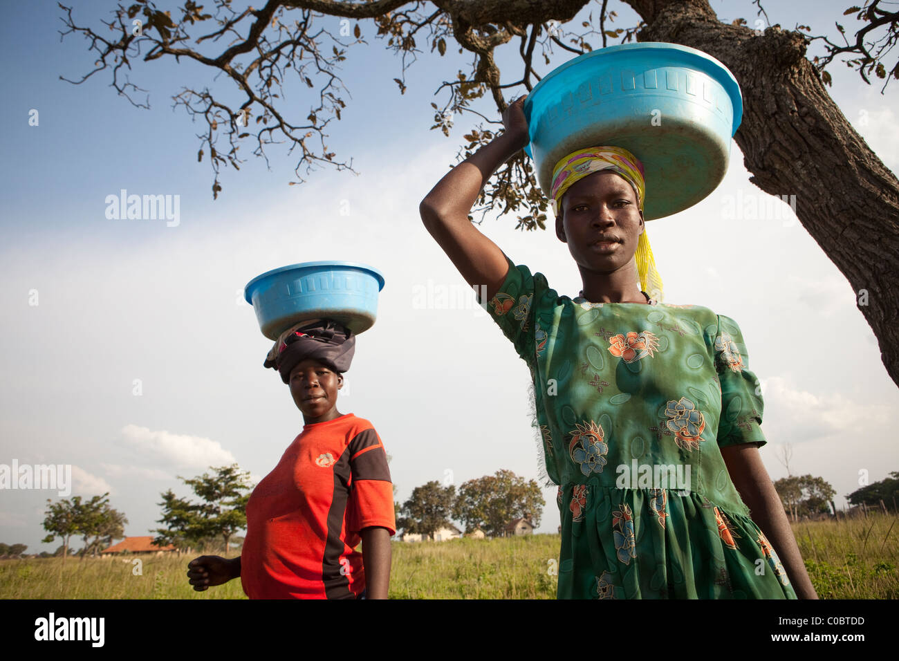 Women carry water containers on their head in Amuria District, Uganda, East Africa. Stock Photo