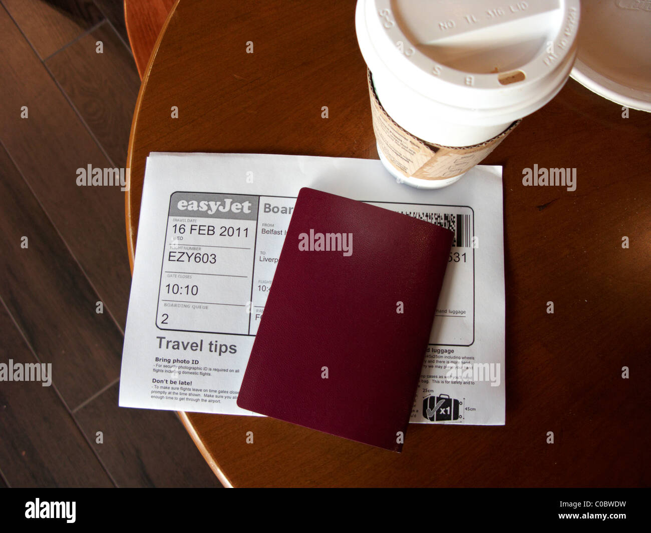 coffee passport and printed boarding card on a table at Belfast International Airport Northern Ireland Stock Photo