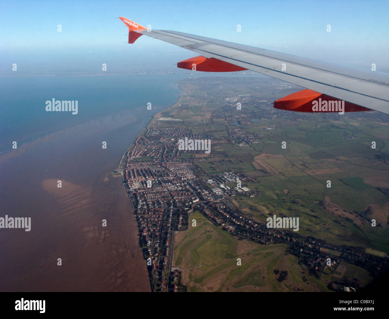 easyjet a319 airbus aircraft wing looking out through aircraft window down at the wirral and liverpool bay Stock Photo
