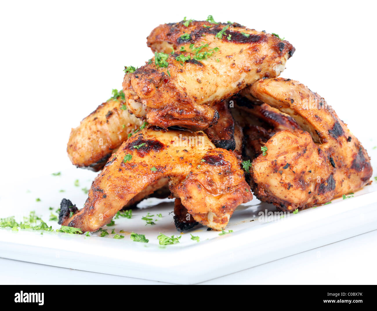 Cooked chicken wings in a sauce on a white plate Stock Photo