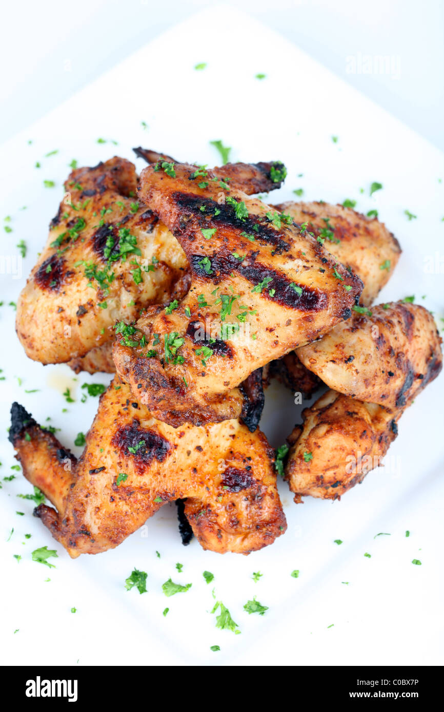 Cooked chicken wings in a sauce on a white plate Stock Photo