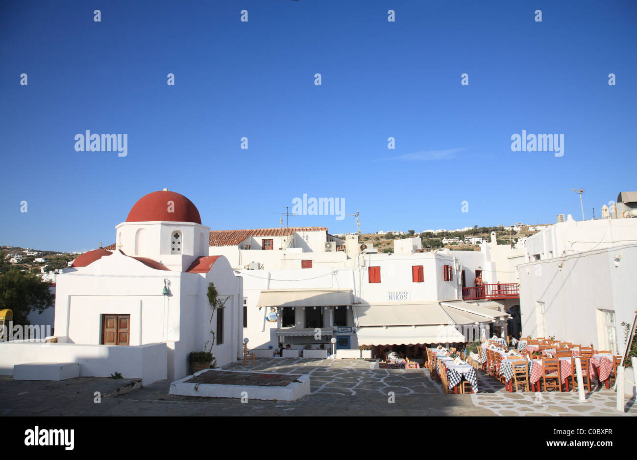 Greek Orthodox Church and Taverna, village square, Mykonos Town (Chora), Mykonos, Cyclades, Greece Stock Photo