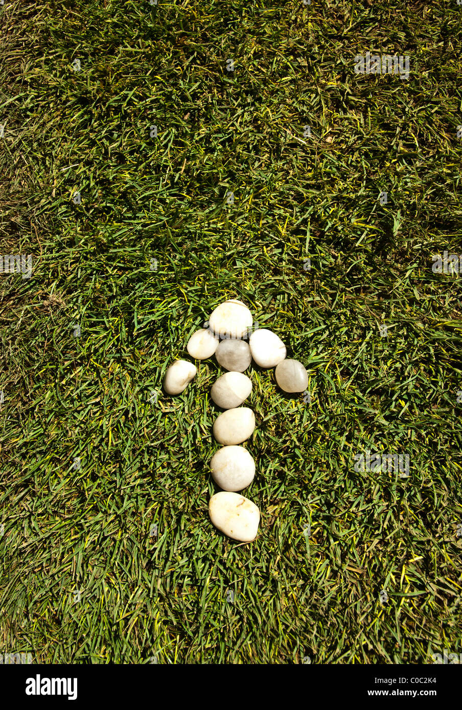 Arrow of white stones on green grass Stock Photo