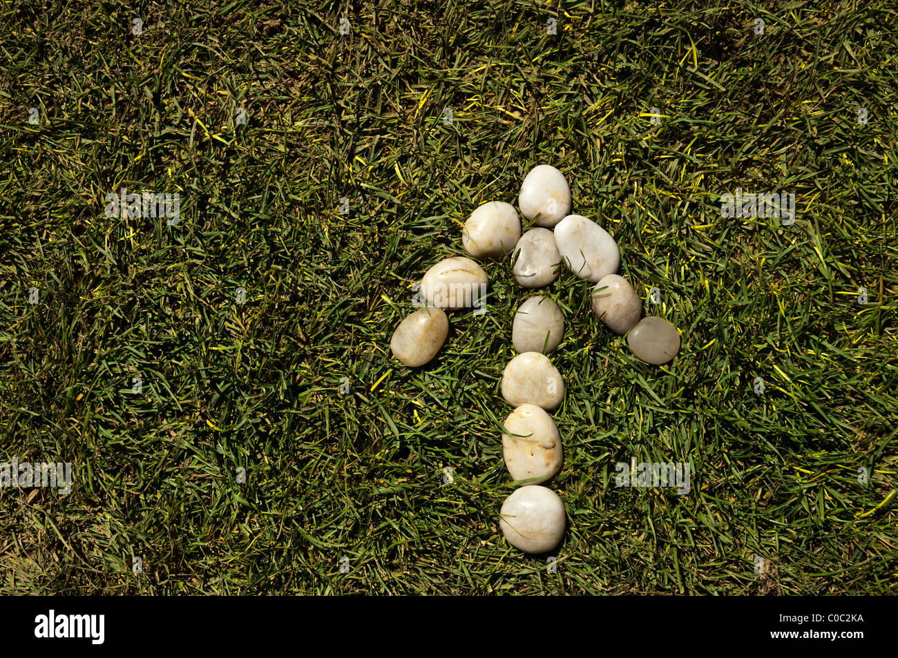 Arrow of white stones on green grass Stock Photo