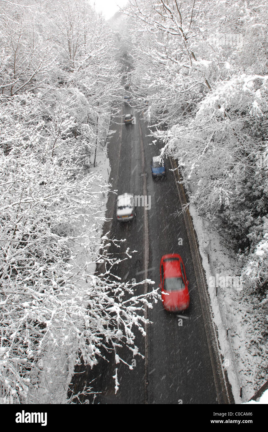 Cars pass on a clear road in East Grinstead as snow falls across the UK