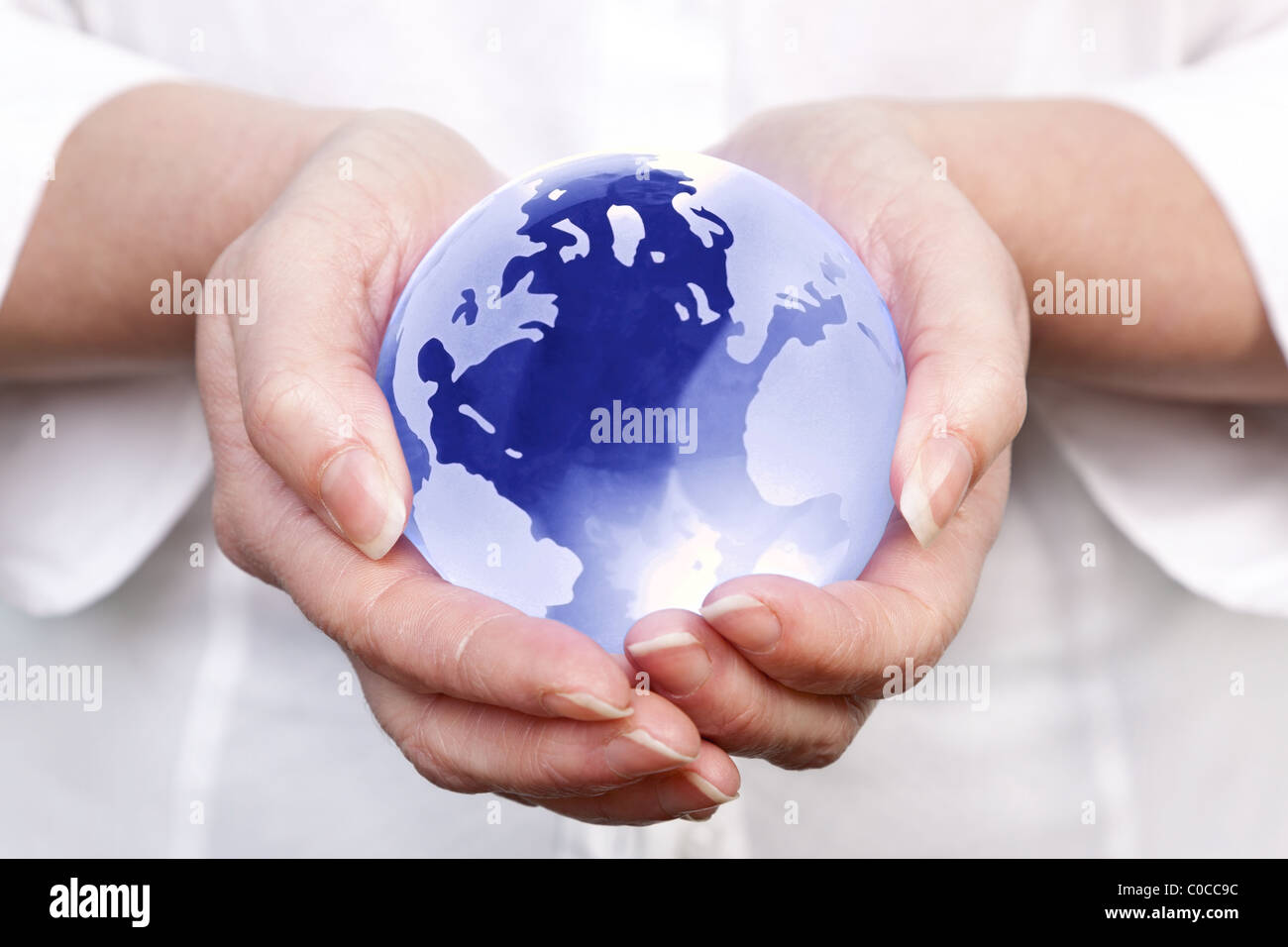 Photo of a woman holding a glass globe in her hands, concept image for worldwide and global related themes. Stock Photo