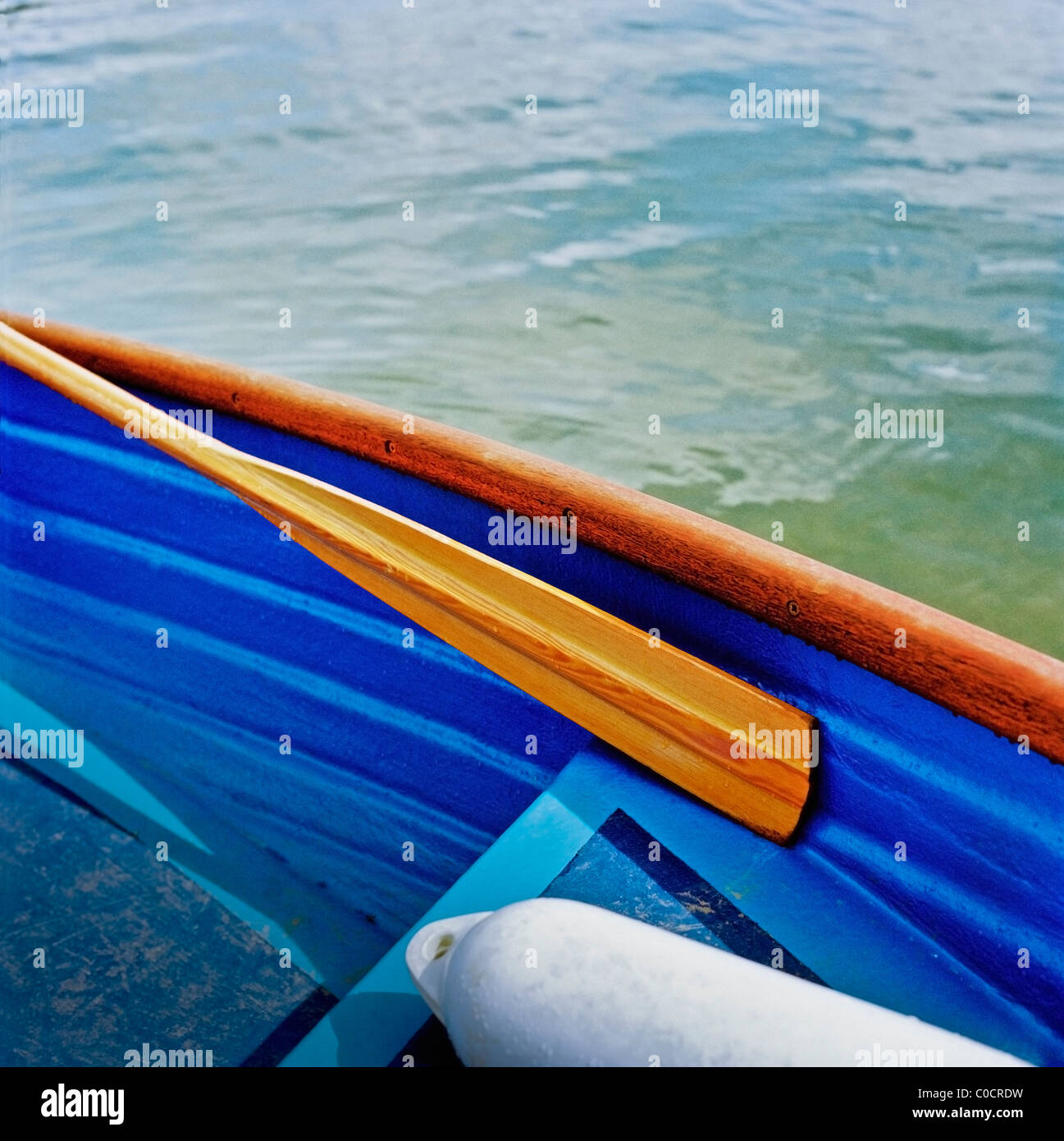 A cropped image of a rowing boat with a buoy and an oar resting inside