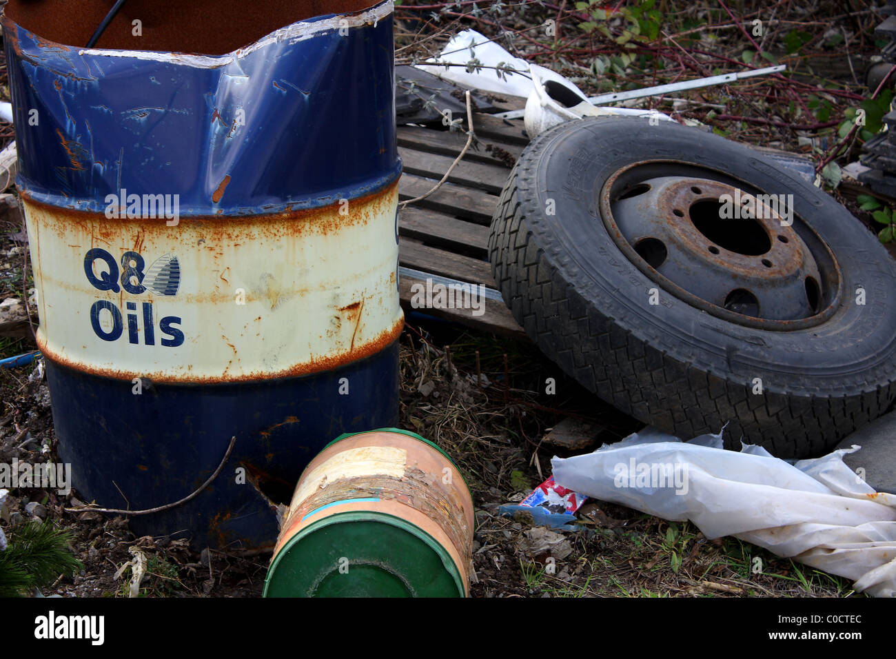 A Q8 oils steel drum, old tyre and other rubbish dumped on Council land. Stock Photo