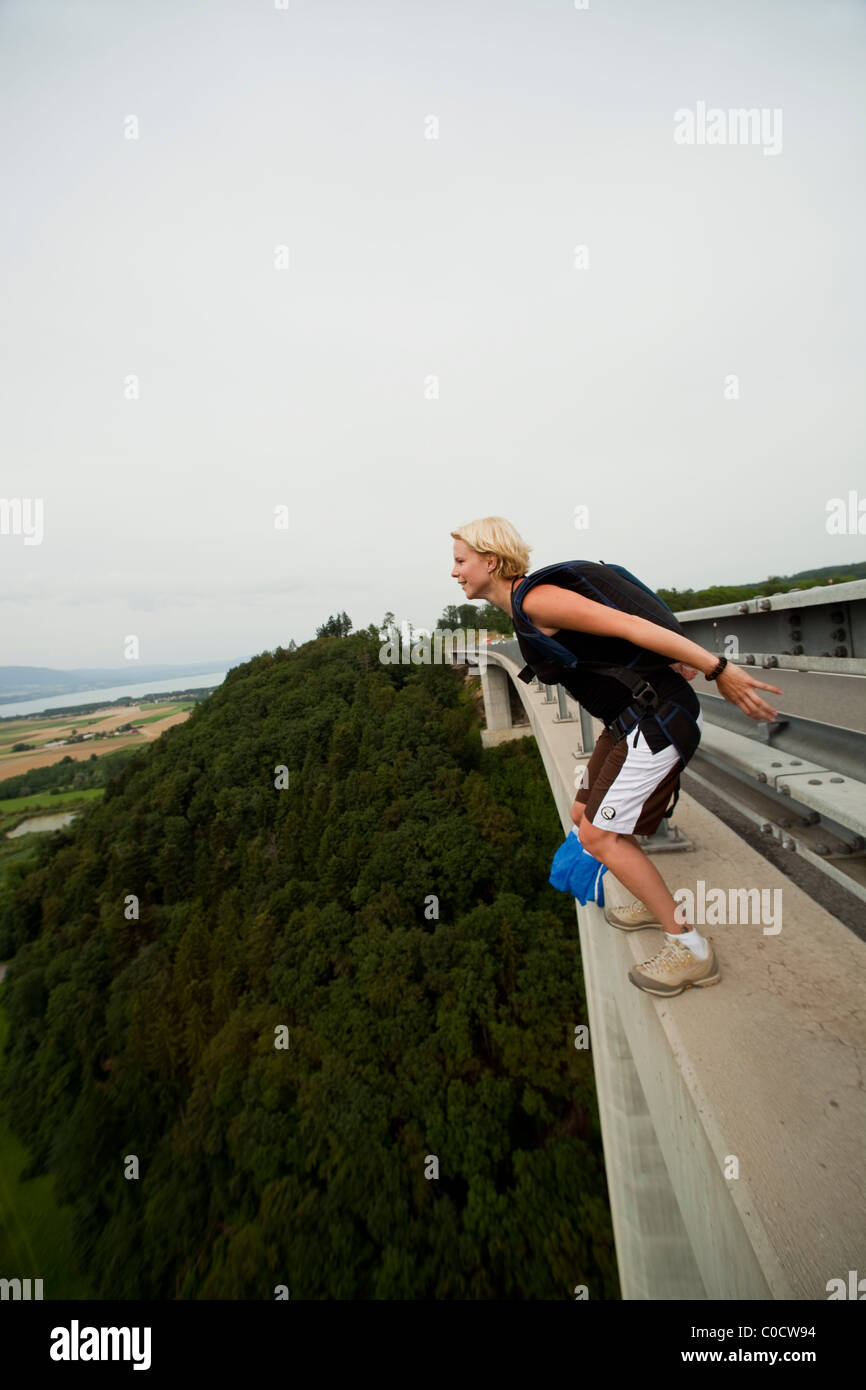BASE jumper girl is going to diving from bridge with a parachute on her back. Stock Photo