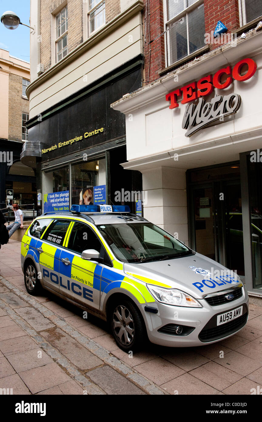 Silver police car parked outside shops on a street in Norwich, Norfolk