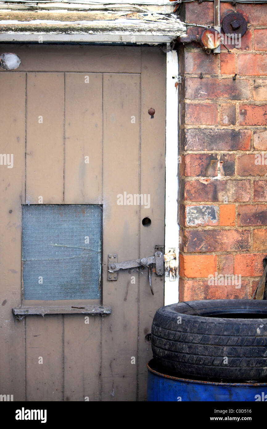 An Old Outhouse With A Wooden Door Latch And A Tyre On An