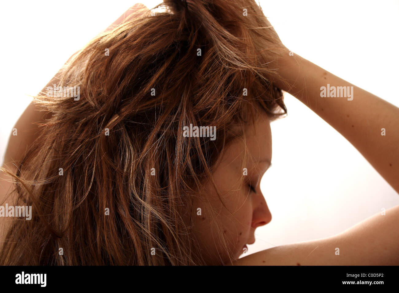 A young woman overworked, stressed and upset, having a bad hair day with a handover due to being drunk the night before. Stock Photo