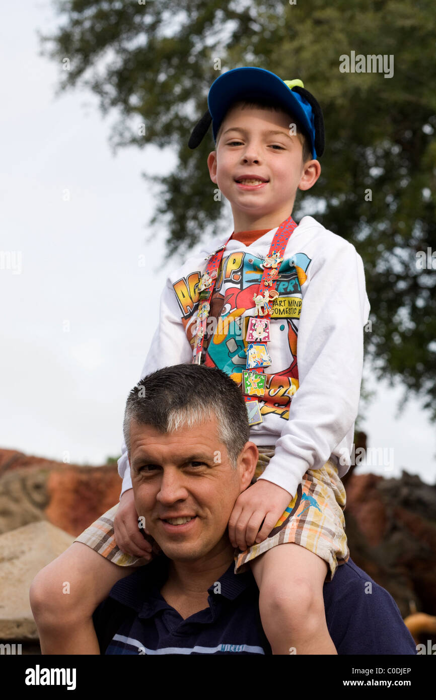 A boy sits on his father's shoulders and proudly displays his Disney trading pins, a popular collecting item at Disney World. Stock Photo