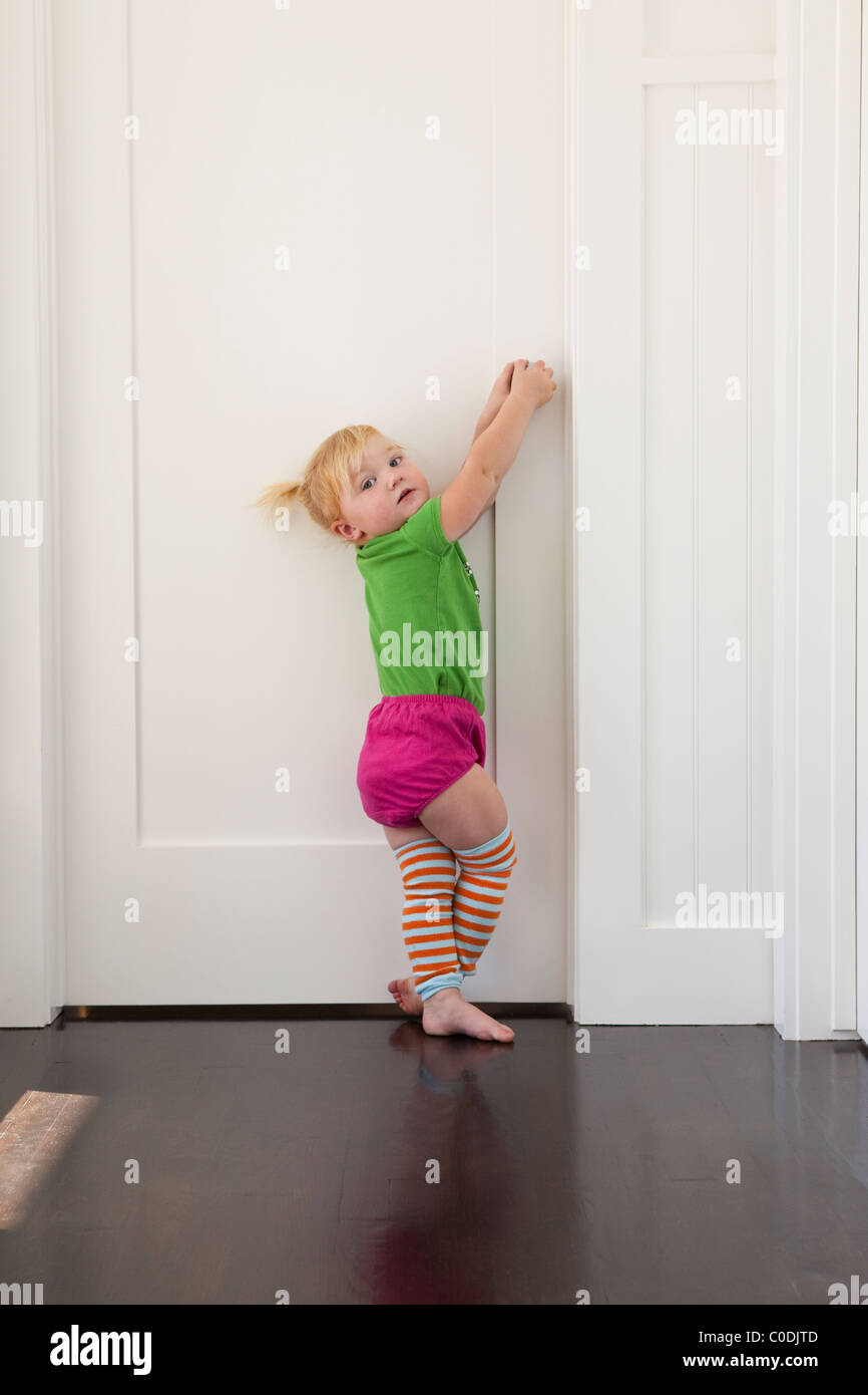 Little girl trying to get in closed door Stock Photo
