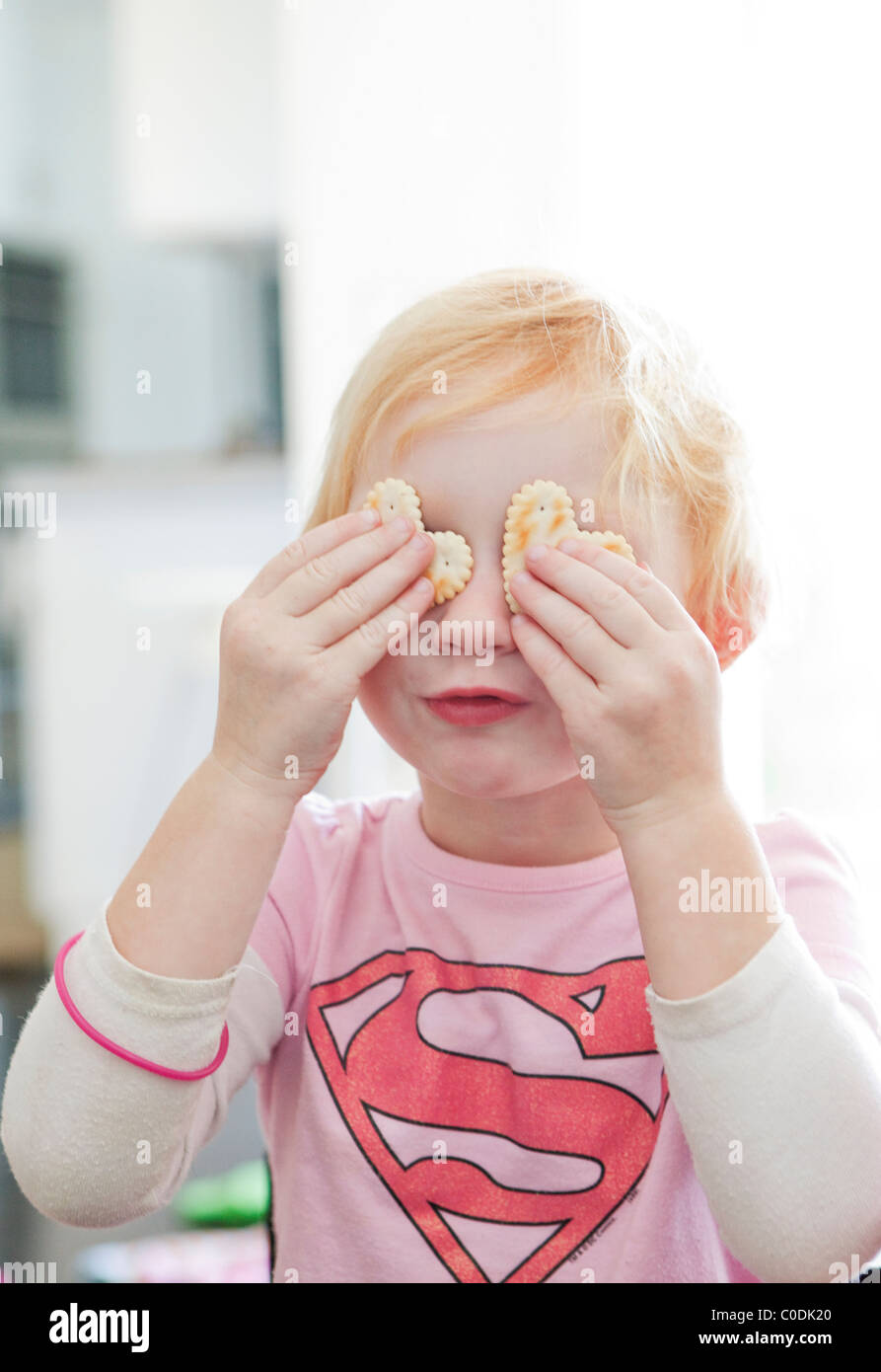 Little girl with crackers on her eyes Stock Photo