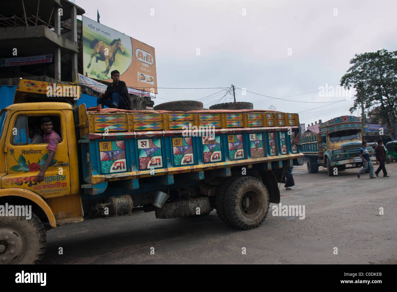 Bangladeshi trucks illustrated with paintings driving through a busy intersection on the Chittagong Highway Stock Photo
