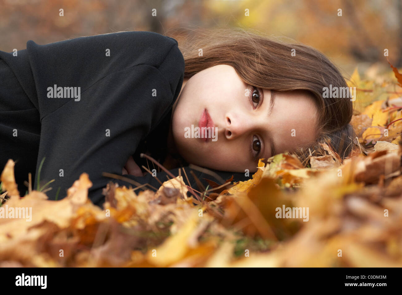 Child laying in fallen leaves Stock Photo