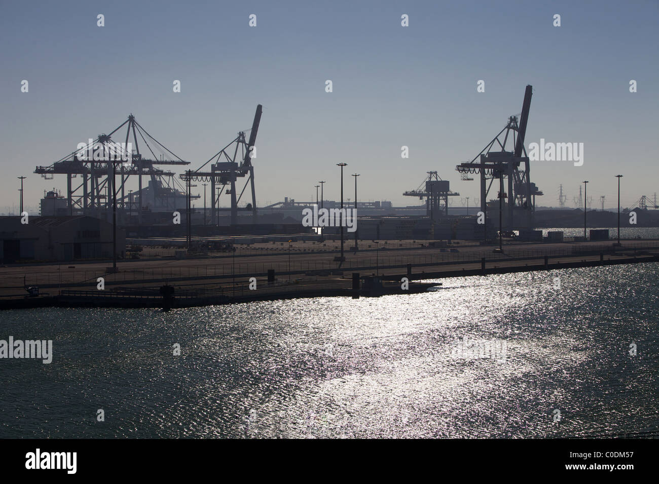 Evening view of an industrial container port with cranes and containers in the background Stock Photo
