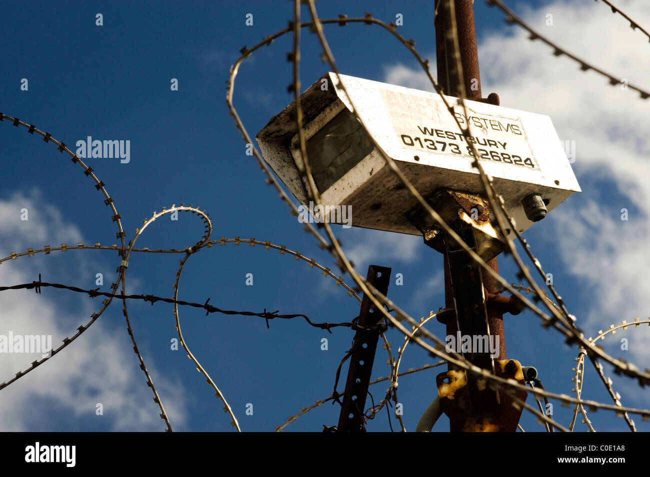 cctv security camera surrounded by razor wire against a blue sky Stock ...