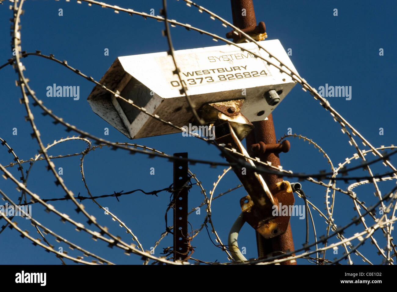 cctv security camera surrounded by razor wire against a blue sky Stock ...