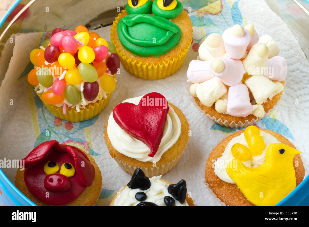 A variety of vibrant fun homemade cup cakes stored in a tin. Stock Photo